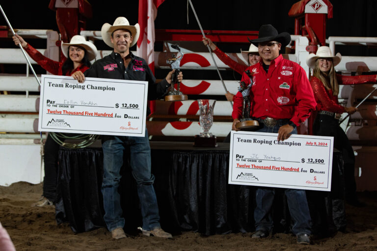 J.C. Yeahquo and Kollin VonAhn pose with their checks and bronze statues for winning the 2024 Calgary Stampede's Rocky Mountain Cup.